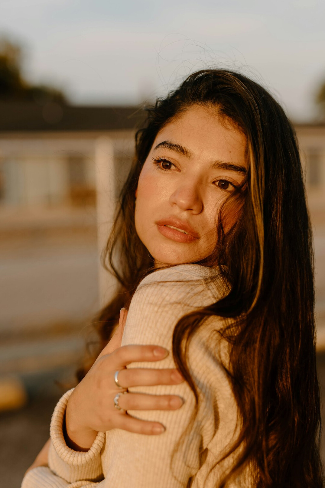 Portrait of a woman with long dark hair wearing a light sweater and smiling